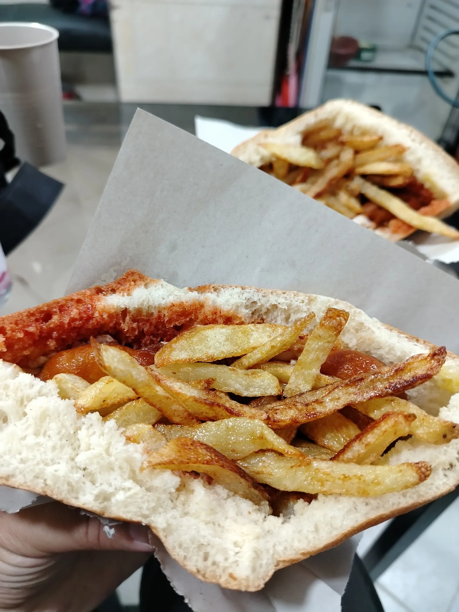 Sandwich garni de frites tenu à la main au Tonic Club